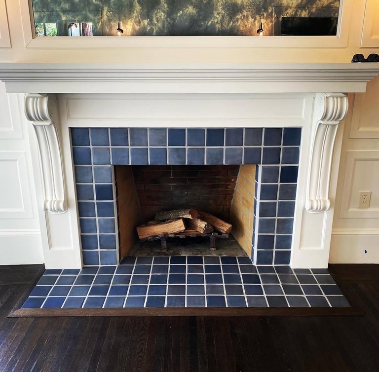 White fireplace with blue tile surround and dark wood floor
